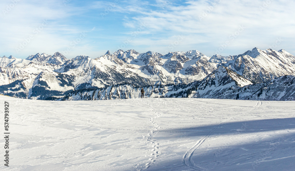 Man is snowshoe hiking with amazing view to alpine winter mountains landscape. Ifersguntalpe, Vorarlberg, Austria.
