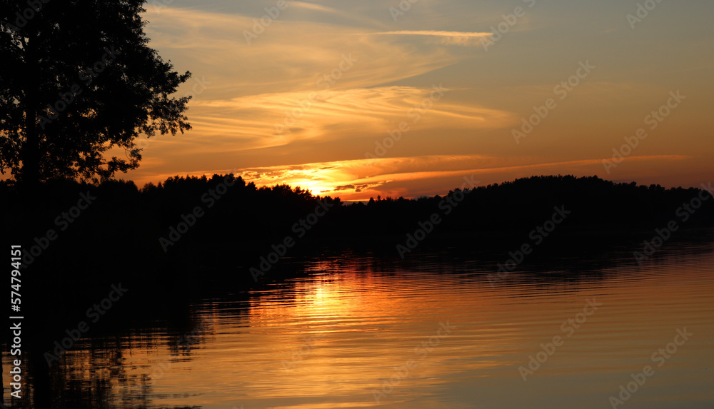 Zachód słońca nad jeziorem z lasem w tle