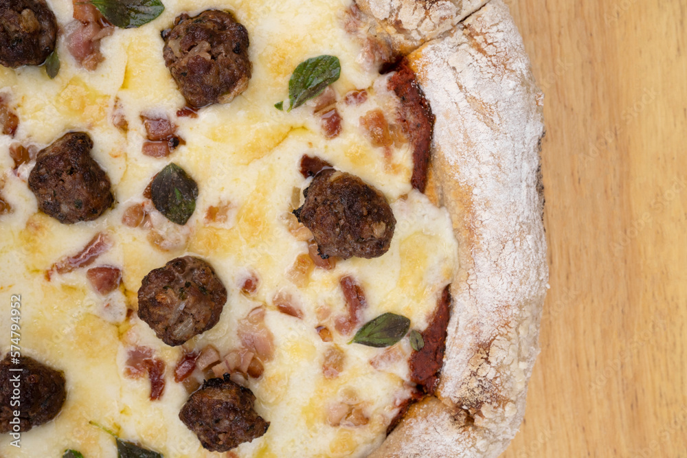 Top view of a delicious pizza with mozzarella cheese, crispy bacon, tomato sauce and meatballs. Top view of a delicious pizza with mozzarella cheese, crispy bacon, tomato sauce and meatballs.