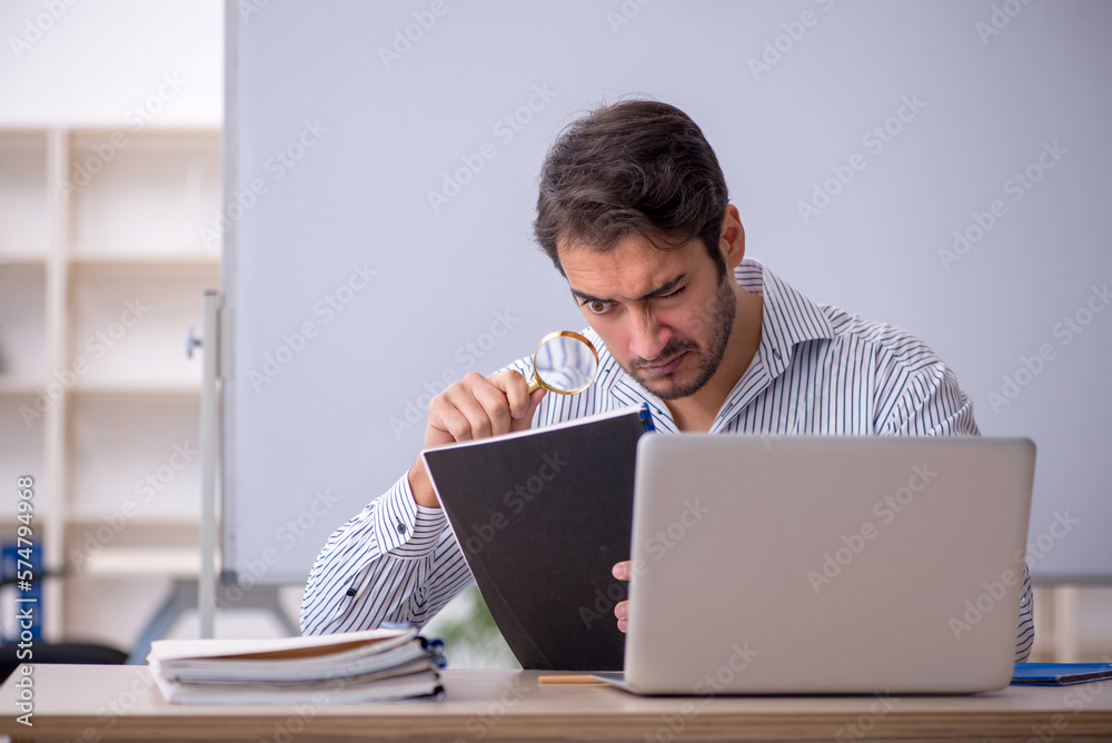 Young male teacher sitting in the classroom Young male teacher sitting in the classroom