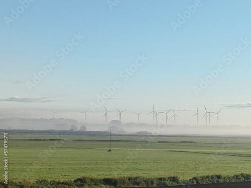farma wiatrowa na polu w oddali za mgłą