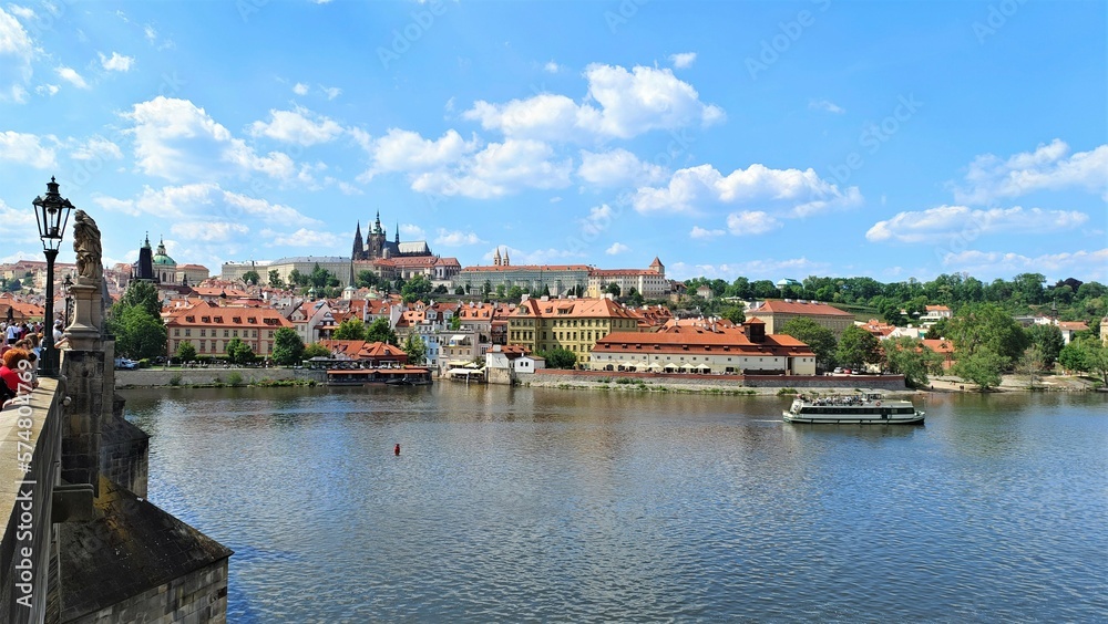 On the banks of the Vltava are the palaces, temples and buildings of the city of Prague. On the river ships take tourists for a ride. The city has many trees. Sunny weather