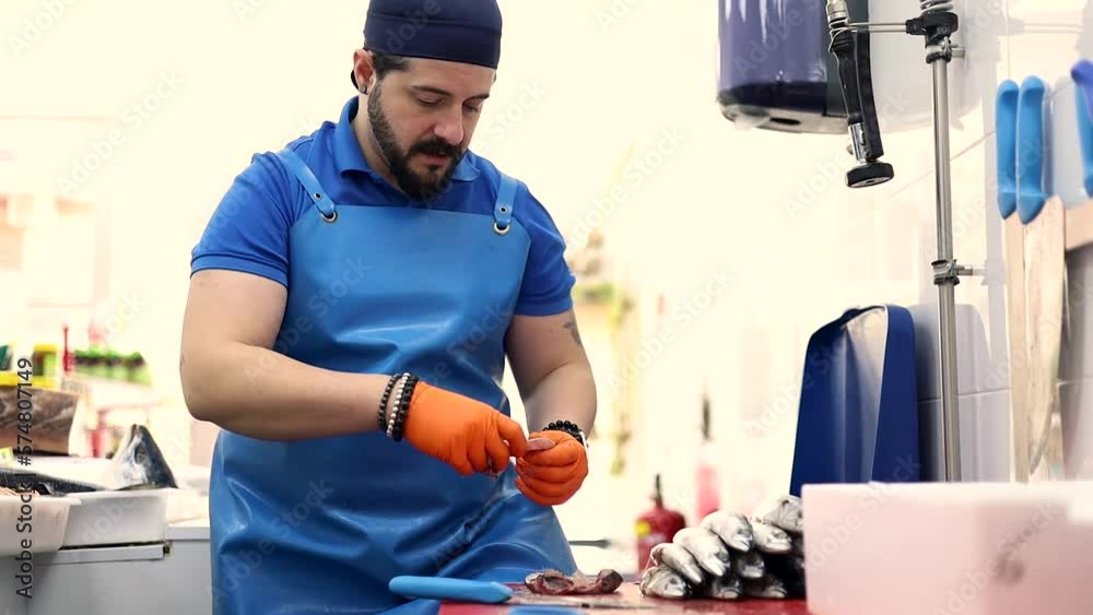 A middle-aged fishmonger is cleaning fish while talking to a partner, selling food, small and medium-sized business. A middle-aged fishmonger is cleaning fish while talking to a partner, selling food, small and medium-sized business.