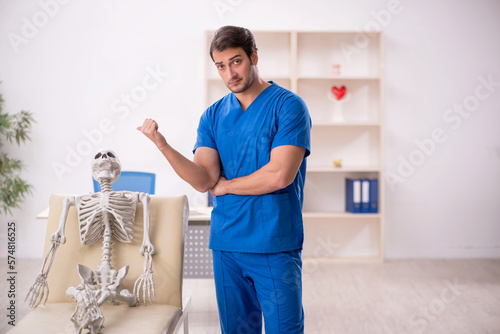 Young male doctor and skeleton patient in the clinic