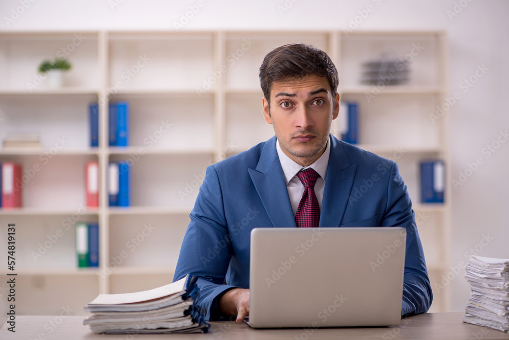 Young male employee and too much work in the office Young male employee and too much work in the office