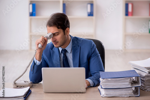 Young male employee and too much work in the office