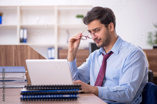 Young male employee unhappy with excessive work at workplace