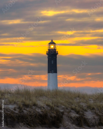 Vibrant colorful sunset sky behind a tall stone lighthousze beacon. Fire Island, Long Island New York