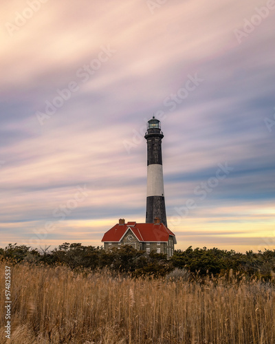 Streaky wispy colorful sunset clouds behind a stone lighthouse. Fire Island  Long Island New York