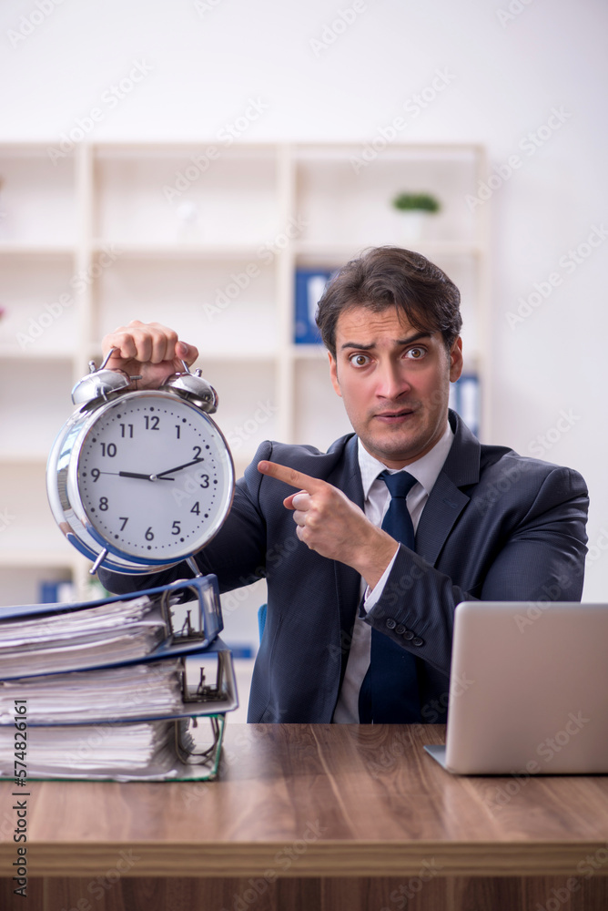 Young male employee in time management concept Young male employee in time management concept