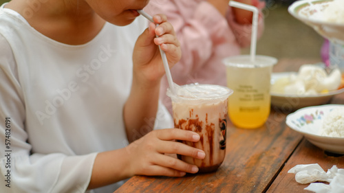 asian child girl drinking milkshake with plastic glass and straw.