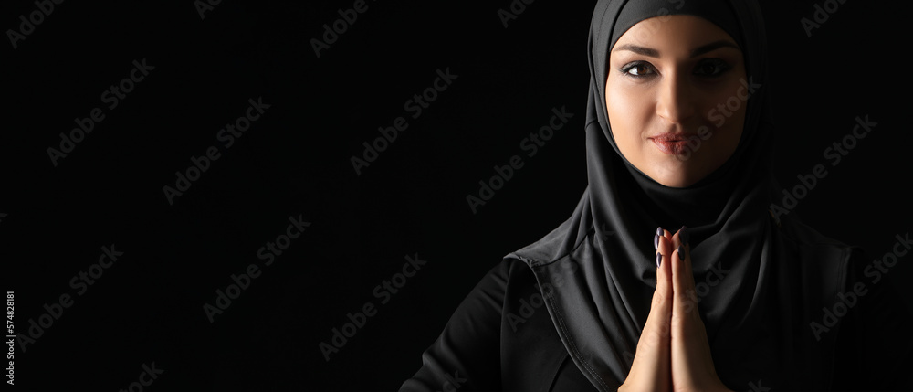 Praying beautiful Arabian woman on dark background with space for text