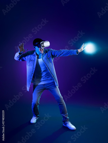 Young man using VR glasses on dark color background © Pixel-Shot