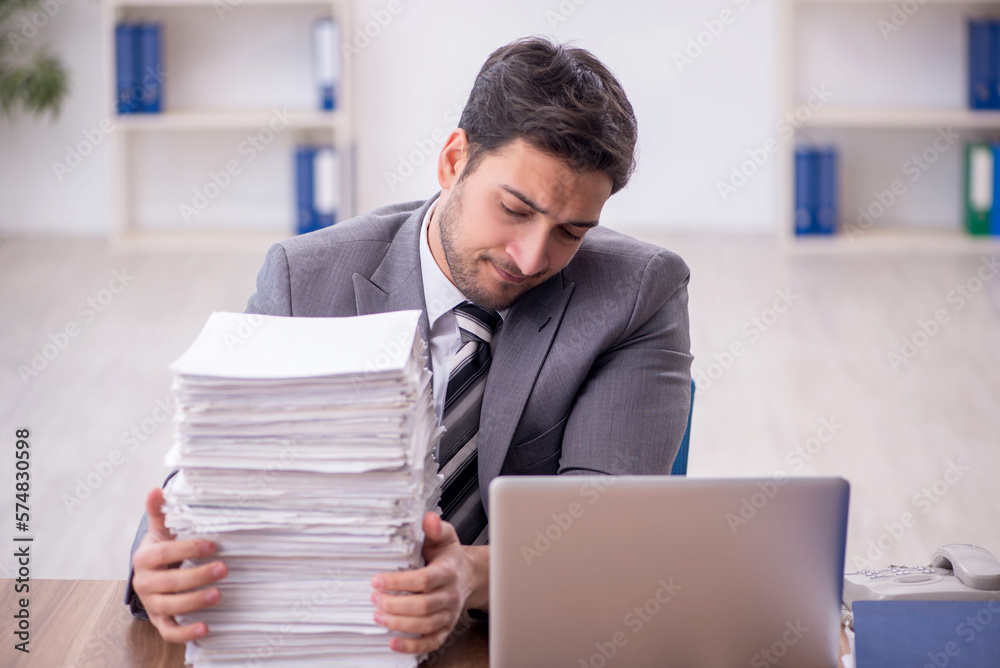 Young male employee and too much work in the office Young male employee and too much work in the office