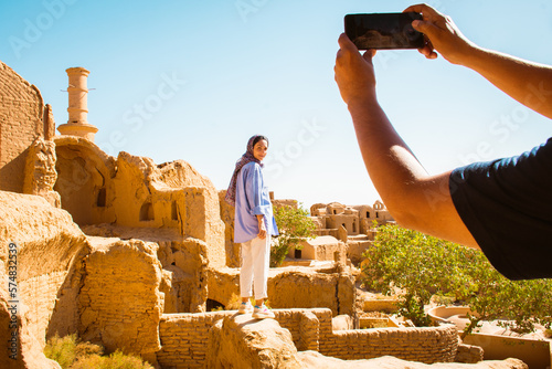 Caucasian woman tourist stand on viewpoint by abandoned mud brick city Kharanaq near the ancient city Yazd in Iran photo