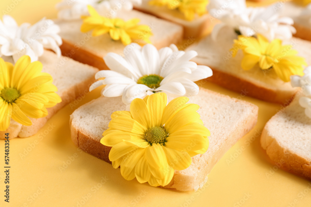 Composition with slices of bread and beautiful chrysanthemum flowers on yellow background, closeup Composition with slices of bread and beautiful chrysanthemum flowers on yellow background, closeup