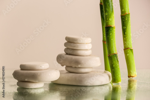 Stacks of spa stones and bamboo on light background