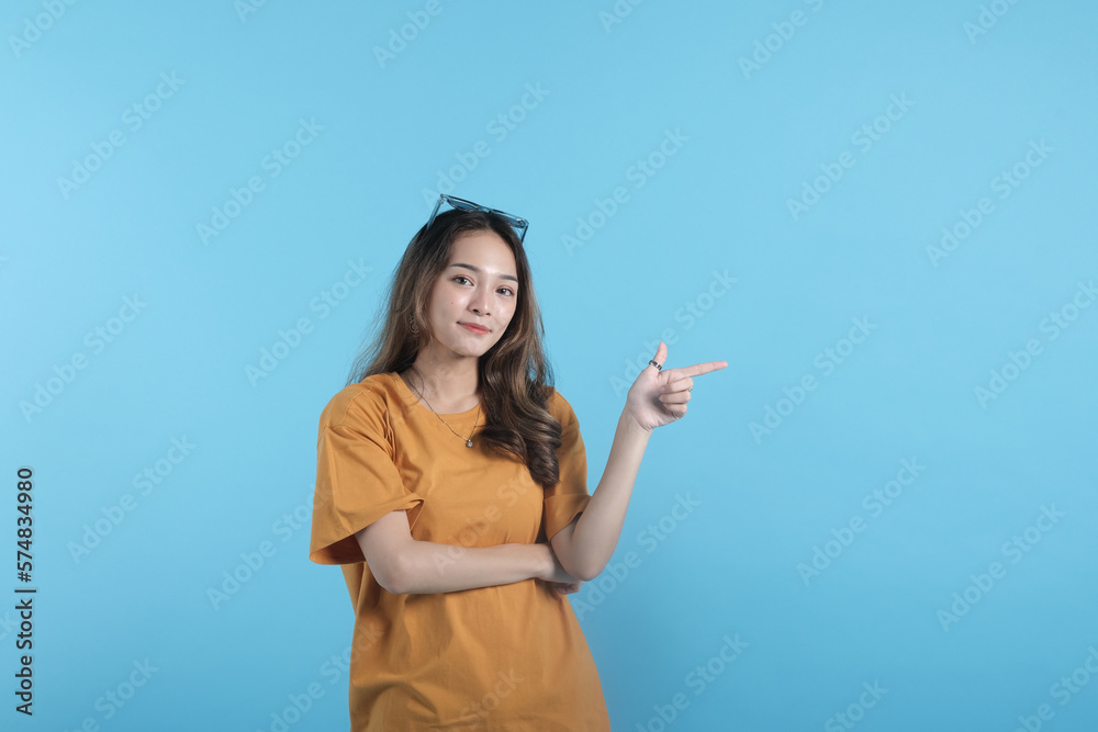 Asian young female using a sunglasses, gesture with her hands pointing to empty space on blue background Asian young female using a sunglasses, gesture with her hands pointing to empty space on blue background