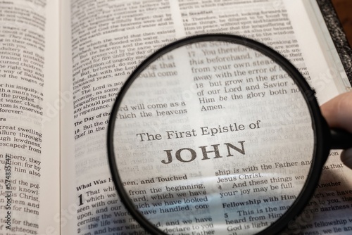title page book of first John close up using magnifying glass in the bible for faith, christian, hebrew, israelite, history, religion, christianity, new testament