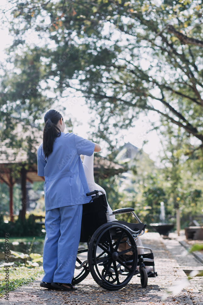 Asian young caregiver nurse support senior older male walking outdoors. Specialist girl doctor help and take care of elderly mature man patient doing physical therapy in public park at nursing home. Asian young caregiver nurse support senior older male walking outdoors. Specialist girl doctor help and take care of elderly mature man patient doing physical therapy in public park at nursing home.