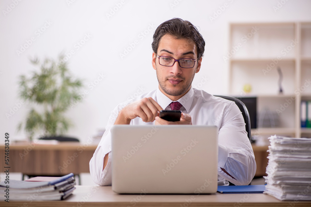 Young male employee and too much work in the office Young male employee and too much work in the office