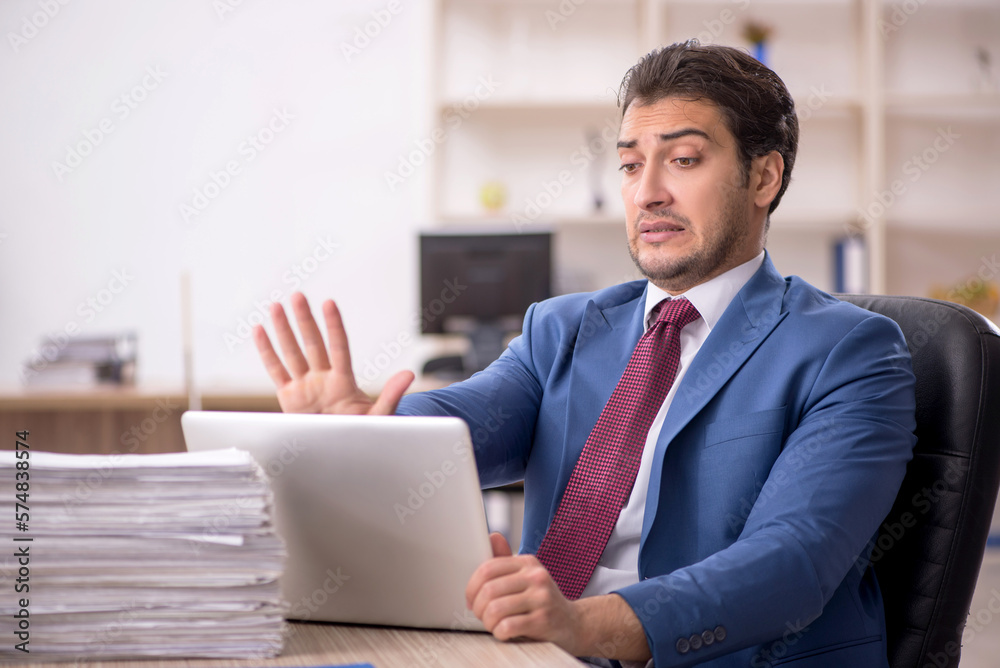 Young male employee and too much work in the office Young male employee and too much work in the office