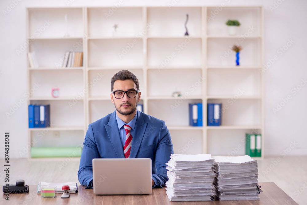 Young male employee unhappy with excessive work in the office Young male employee unhappy with excessive work in the office