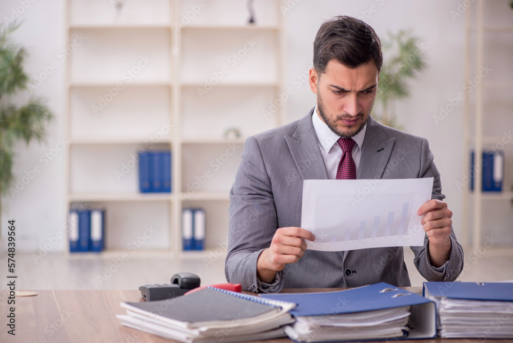 Young male employee and too much work in the office Young male employee and too much work in the office