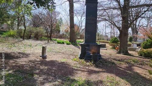 footage of a graveyard with headstones, graves, bare winter trees, lush green trees, plants and grass with blue sky at the Oakland Cemetery in Atlanta Georgia USA photo