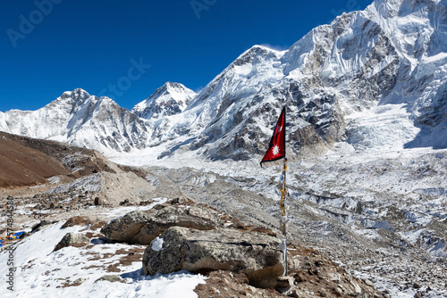 Flag of Nepal on Everest Base Camp Trek. Himalayan landscape with Khumbu glacier and high snowy mountain peaks.