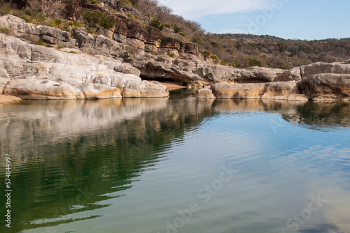 A limestone rock wall creates a small canyon for the pool of green water below in Pedernales Falls State Park as part of the Texas Hill Country © BrigitteT