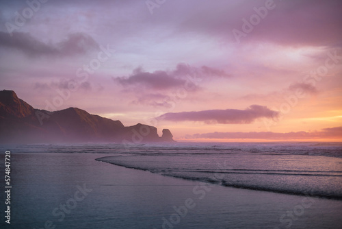 Purple skies and gentle waves at Piha Beach, New Zealand. (ID: 574847720)