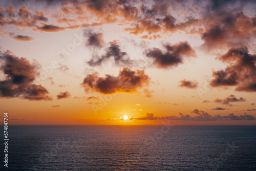 The infinite expanse of the ocean horizon at sunset, as vibrant pink, orange, and purple clouds fill the sky. (ID: 574847764)