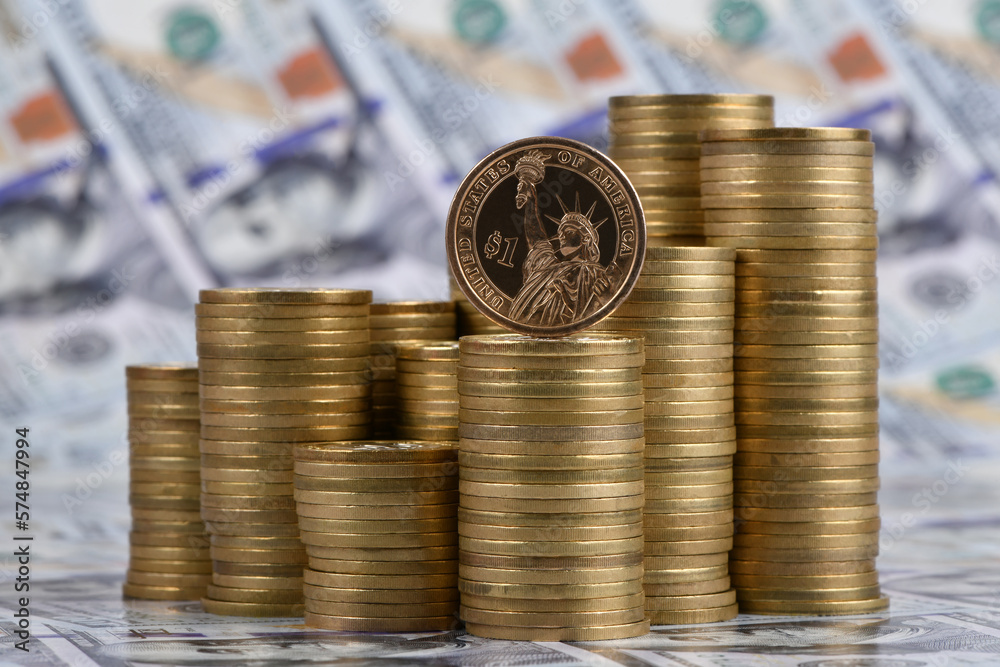 1 US dollar coin and stacks of gold coins against the background of 100 US dollar bills 1 US dollar coin and stacks of gold coins against the background of 100 US dollar bills