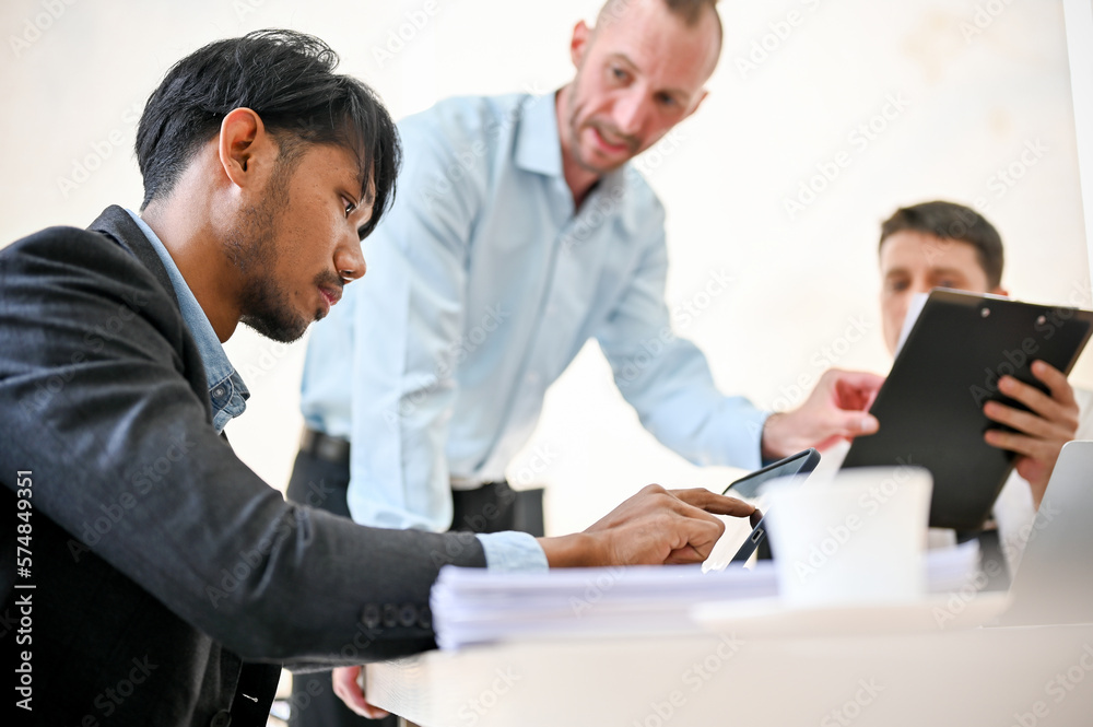 Smart Asian male financial analyst is in the meeting with caucasian bosses. side view Smart Asian male financial analyst is in the meeting with caucasian bosses. side view
