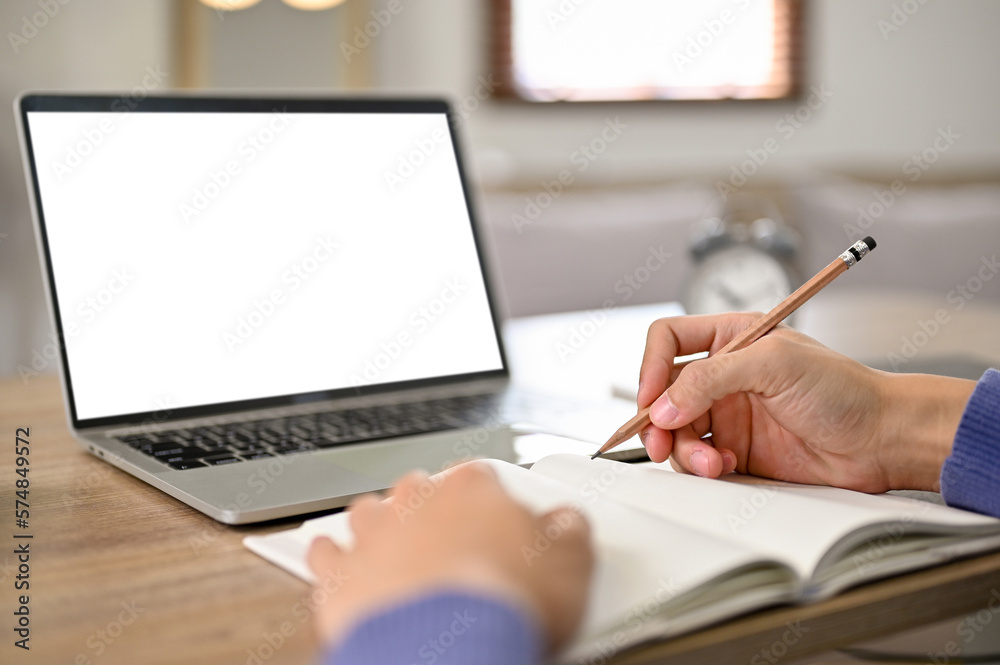 Close-up image of a male student doing homework. laptop white screen mockup Close-up image of a male student doing homework. laptop white screen mockup
