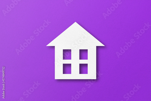 White paper cut out house shape isolated on purple paper background.