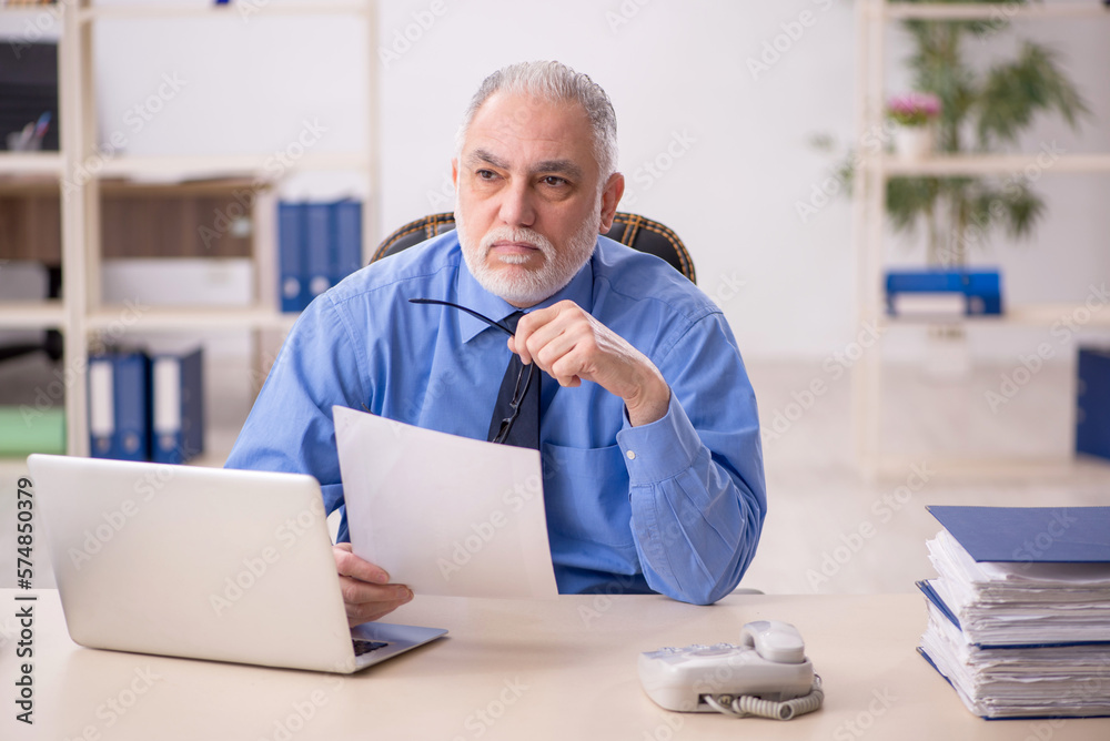 Old male employee working in the office Old male employee working in the office