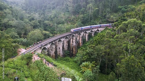 A train runs on Nine Arches Bridge in Sri Lanka, in the middle of a lush jungle photo