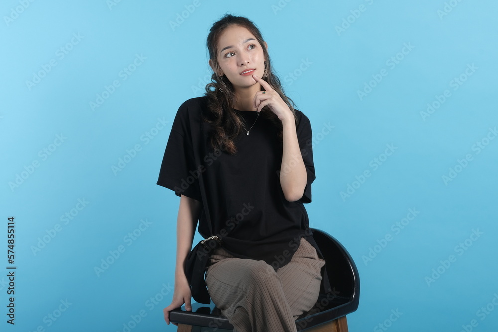 Asian young woman poses to camera wearing black t-shirt on blue background Asian young woman poses to camera wearing black t-shirt on blue background