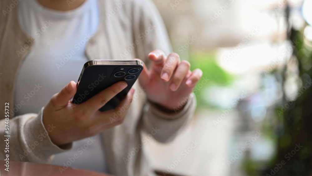 Cropped image of an Asian female relaxing in the city park and using her smartphone. Cropped image of an Asian female relaxing in the city park and using her smartphone.