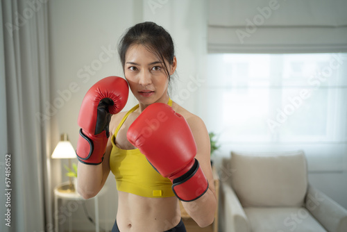 Portrait of strong Asian woman punching bag, combat punches in boxing sport club workout at training gym fitness center at home or house. Exercise indoor sport equipment. People lifestyle. photo