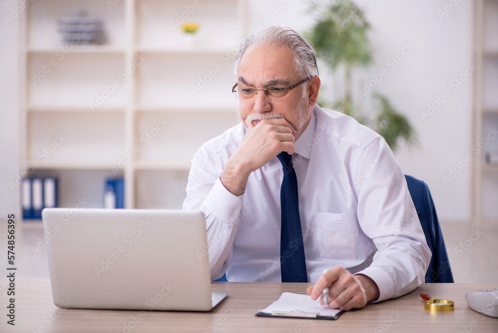 Old male boss working at workplace Old male boss working at workplace