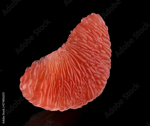 A slice of red grapefruit on a black background. Macro.