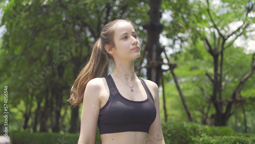 Portrait of Caucasian woman girl in yoga class club doing exercise, runing or jogging at public garden park. Outdoor sport and recreation. People lifestyle activity with nature trees view.