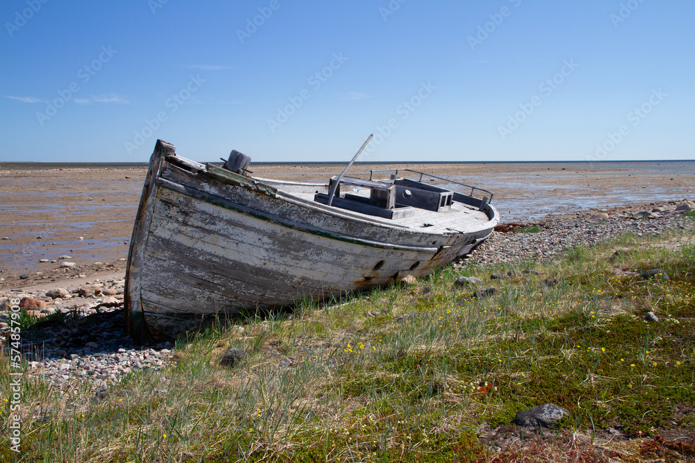 Front view of old wooden boat wrecked and stranded on a rocky shoreline, north of Arviat, Nunavut, Canada Front view of old wooden boat wrecked and stranded on a rocky shoreline, north of Arviat, Nunavut, Canada