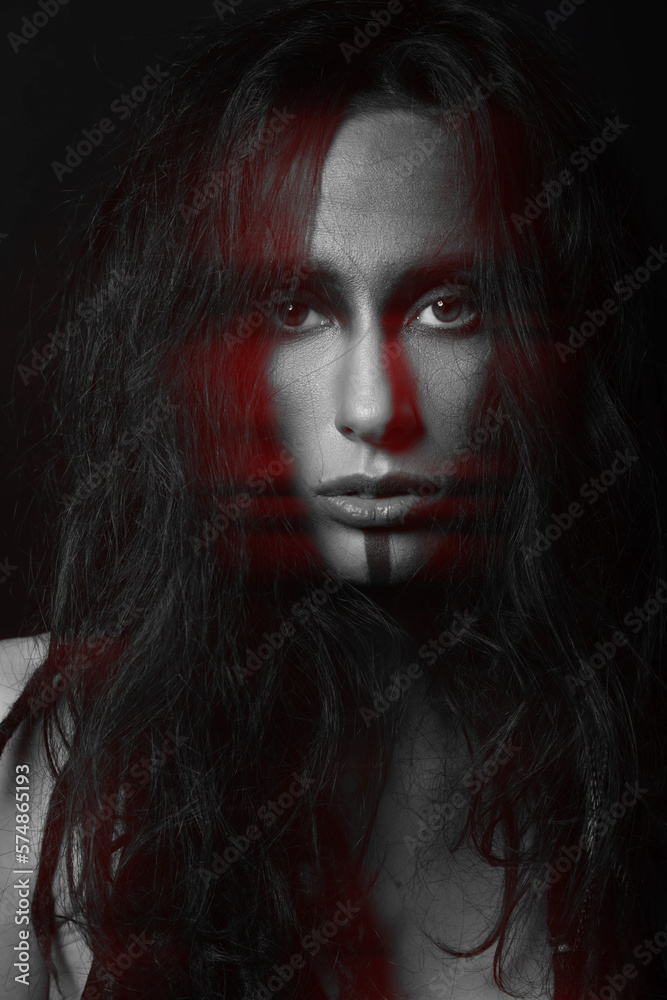 Beautiful woman studio portrait in red color split effect. Model with messy dreadlocks hair and make-up looking to camera with seductive look. Black and white image. Futuristic looking style