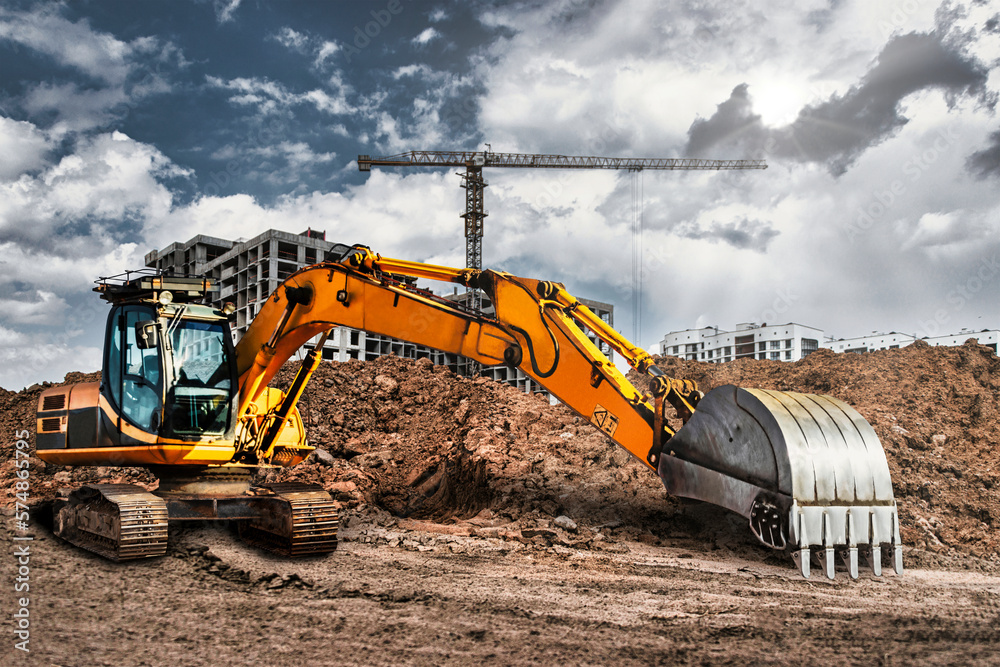 A large yellow crawler excavator moving stone or soil in a quarry. Heavy construction hydraulic equipment. excavation. Rental of construction equipment. A large yellow crawler excavator moving stone or soil in a quarry. Heavy construction hydraulic equipment. excavation. Rental of construction equipment.
