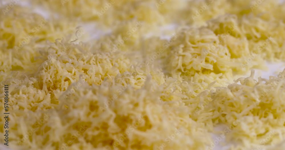 Hard cheese with holes grated into thin small slices, small pieces of cheese for pizza and snacks