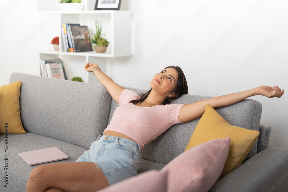 Happy young woman resting with her arms outstretched, on the couch Happy young woman resting with her arms outstretched, on the couch